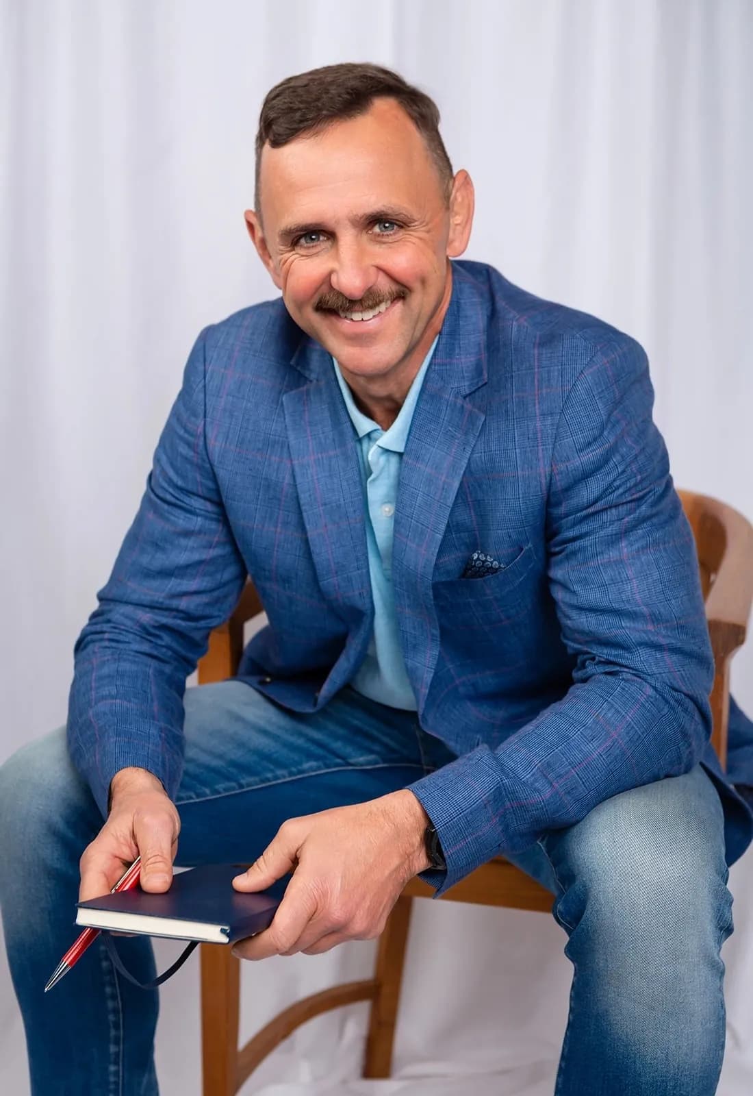 Steve Mudge seated in a blue blazer reviewing notes, business advisor for custom home builders